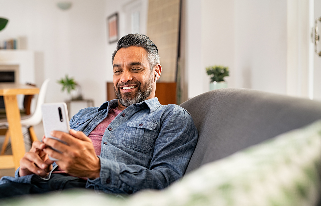 man sitting on couch looking at mobile phone