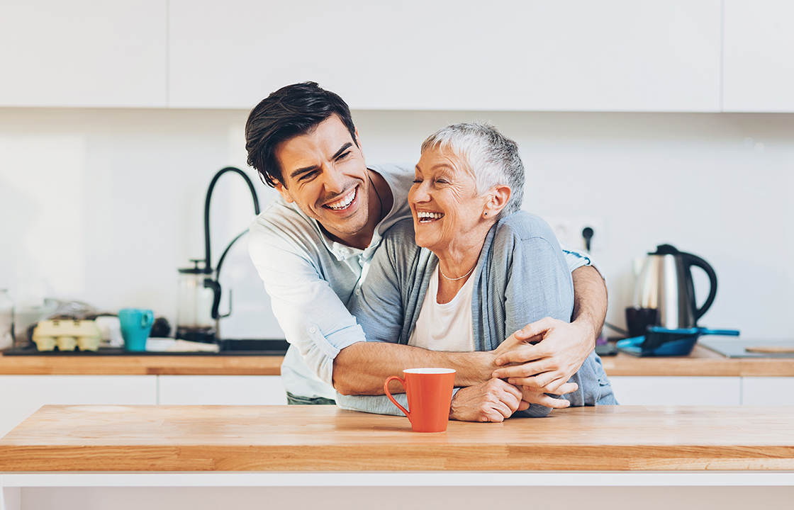 young man hugging senior lady in kitchen