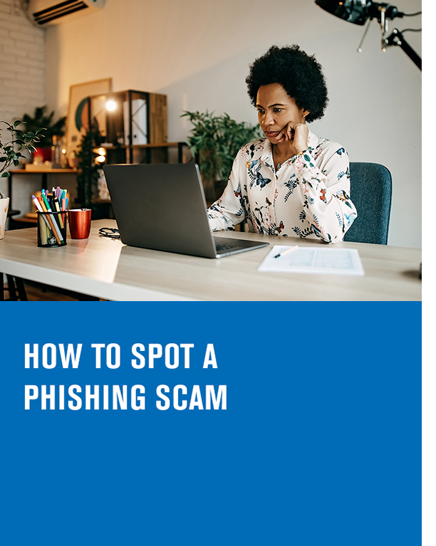 woman sitting at a desk behind a laptop with the article title text how to spot a phishing scam