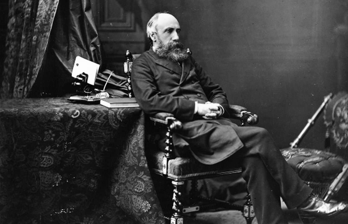 Photo de profil de George Hague, premier président de l'ABC, assis les jambes croisées, prise en en 1879 