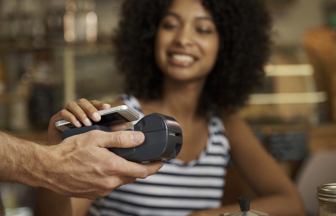 woman using cell phone to make a payment on a POS machine