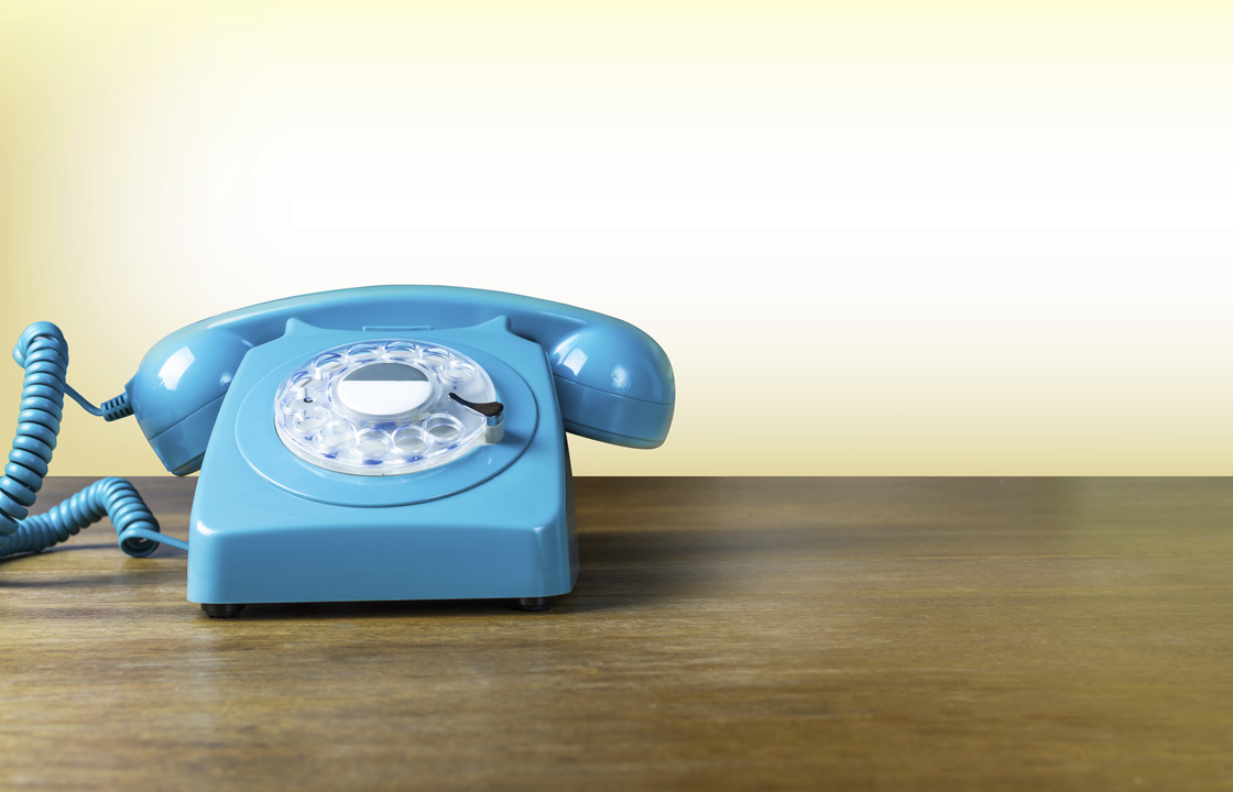 blue rotary style phone on a wood counter