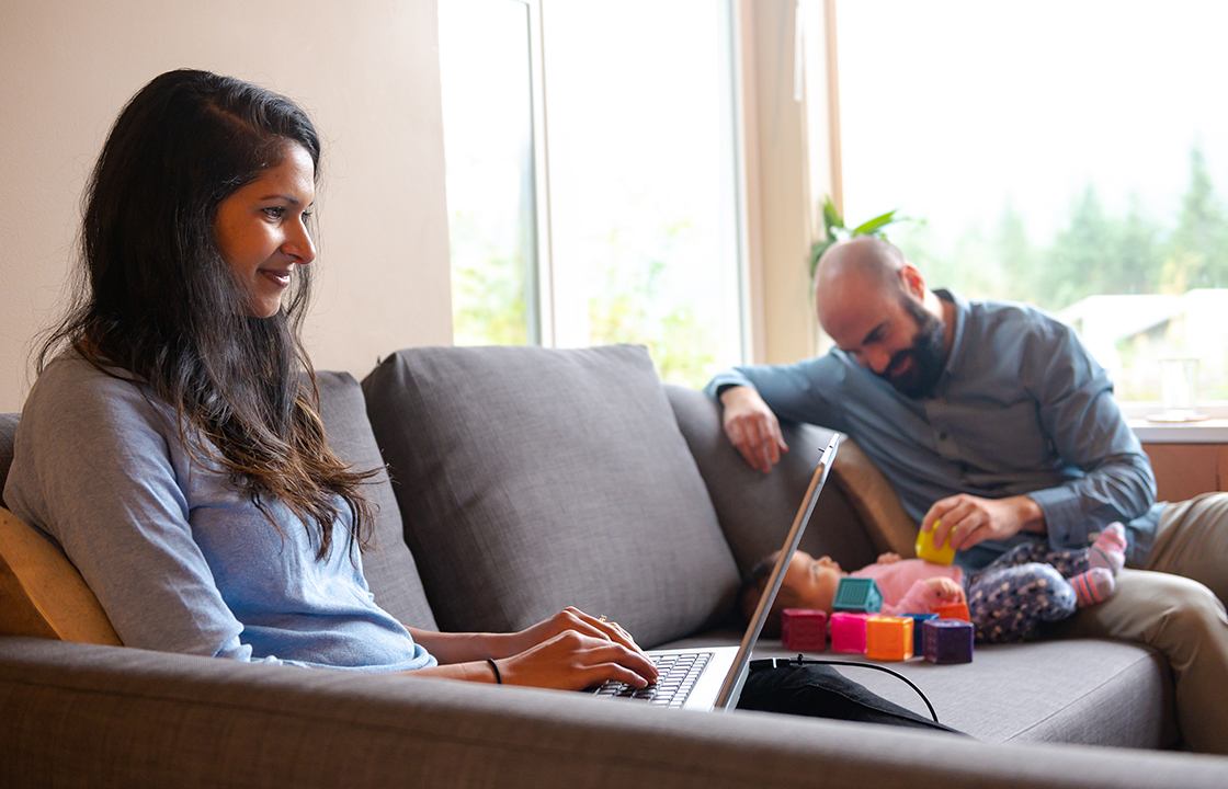 couple with baby sits on couch