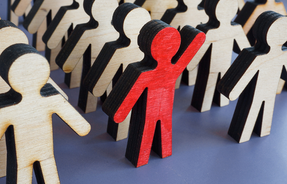 wooden people with one standing out in red