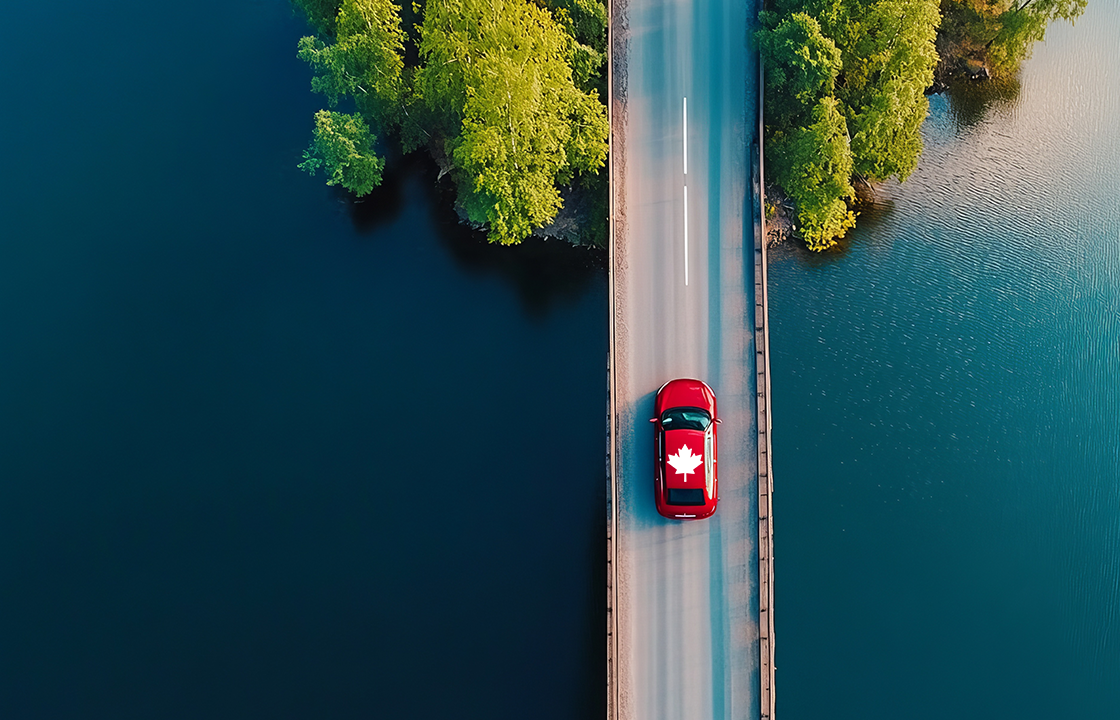 decorative: car with maple leaf on the roof driving on a bridge with water on either side